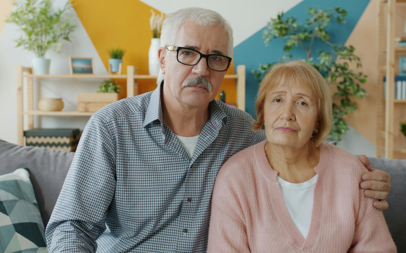 Elderly couple sitting on a couch indoors. by Vitaly Gariev courtesy of Unsplash.